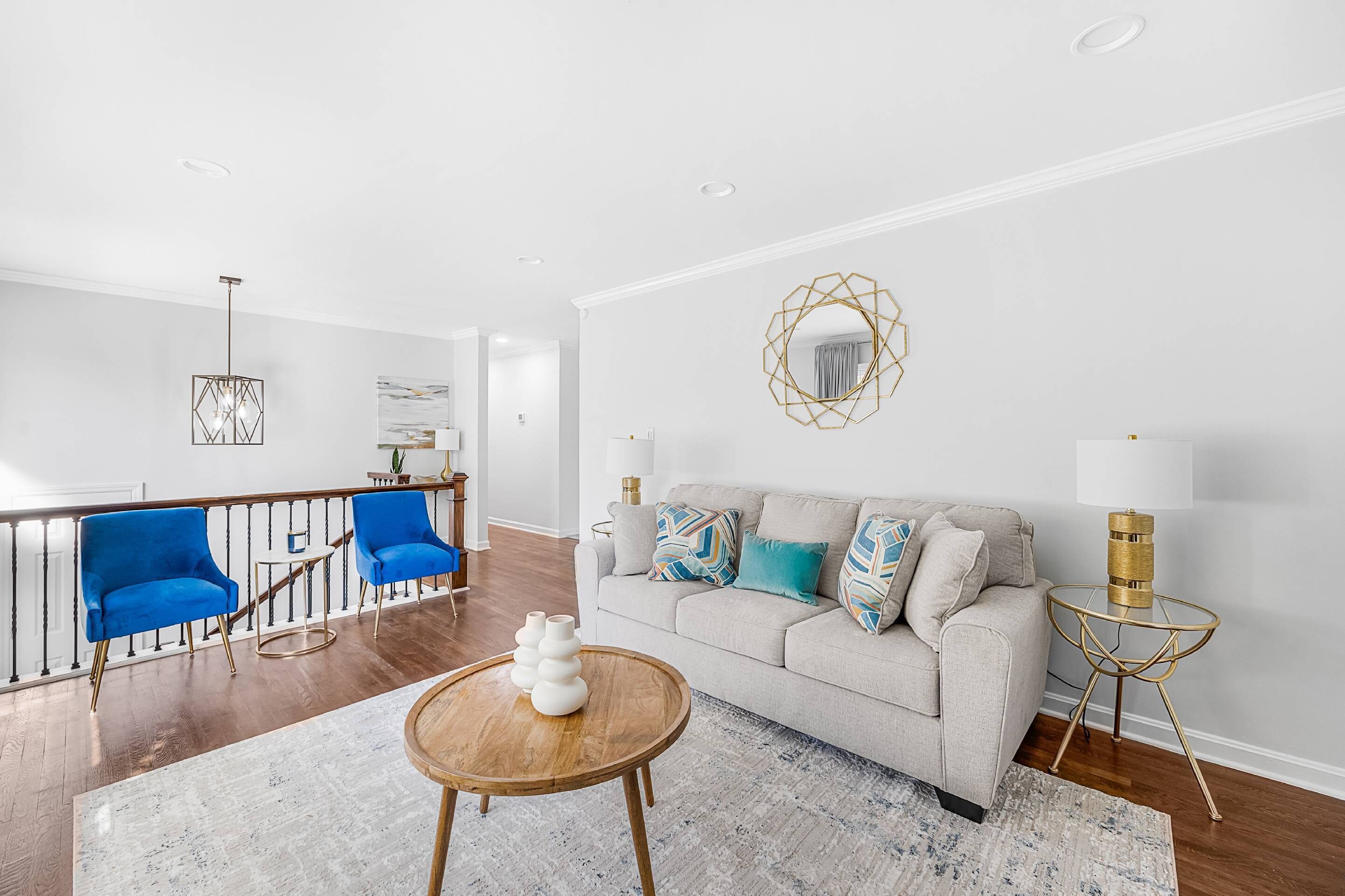 A modern living room with a sofa, two blue chairs, a coffee table, and a decorative mirror.