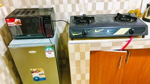 A compact kitchen with a microwave, a small refrigerator, and a gas stove. - Lux Suites Polytech Court Apartments (Nairobi)