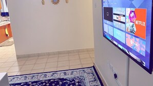 A living room with a flat-screen TV mounted on the wall displaying a streaming service interface. - Lux Suites Polytech Court Apartments (Nairobi)