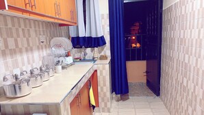 A narrow kitchen with a tiled backsplash, a sink, and a countertop with storage containers. - Lux Suites Polytech Court Apartments (Nairobi)