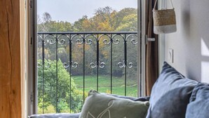 A view from a window with a wrought iron balcony, a green cushion with a leaf design, and a glimpse of a green landscape outside. - Le Château de Kergonano by Interhome (Baden)