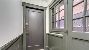 A hallway with a dark door, a window with multiple panes, and a textured carpet.