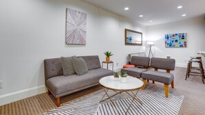 A modern living room with a grey sofa, two armchairs, a coffee table, and a patterned rug.