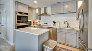 A modern kitchen with stainless steel appliances, white cabinetry, and a central island. - Waterfront Gloucester Cottage w/ Private Boat Dock (Gloucester)