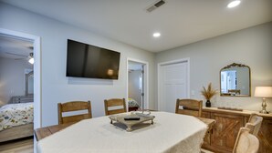 A dining area with a wooden table, chairs, and a TV mounted on the wall. - Waterfront Gloucester Cottage w/ Private Boat Dock (Gloucester)