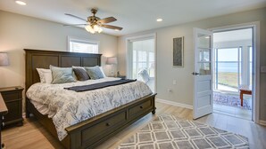 A bedroom with a bed, bedside tables, a ceiling fan, and a view to the outside. - Waterfront Gloucester Cottage w/ Private Boat Dock (Gloucester)