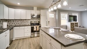 A modern kitchen with white cabinets, a stainless steel oven, a microwave, and a granite countertop. - Lake Charles Home w/ Gas Grill & Fenced-In Yard! (Lake Charles)
