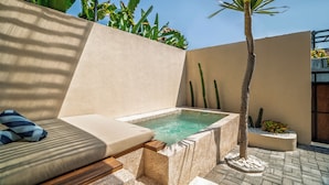 Een wellnessruimte met een jacuzzi, een comfortabele zithoek en een kleine palmboom.