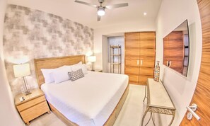A bedroom with a bed, bedside tables, a mirror, a wardrobe, and a ceiling fan.