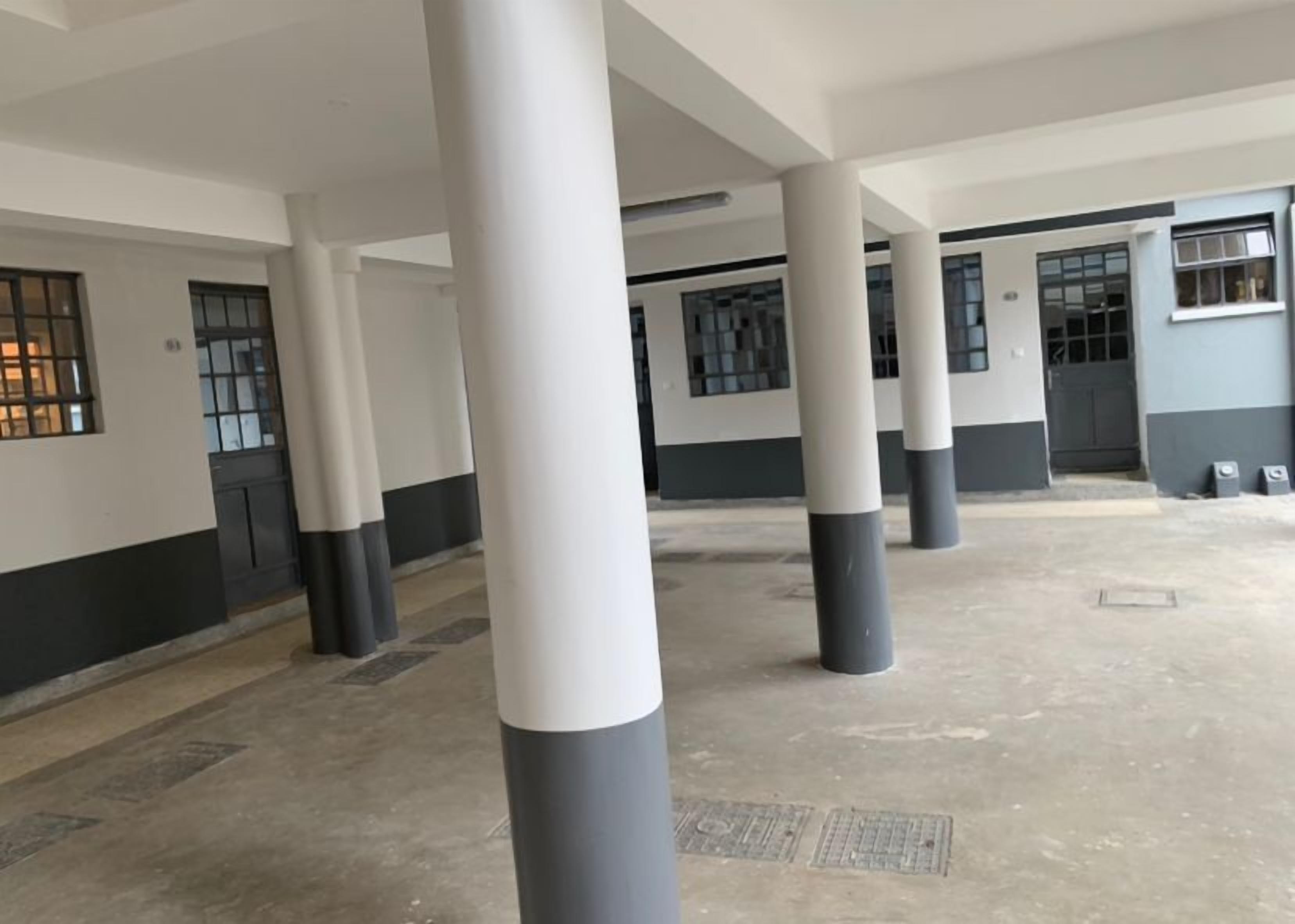 Un vaste espace intérieur doté de hauts plafonds et de colonnes, avec de grandes fenêtres et portes.