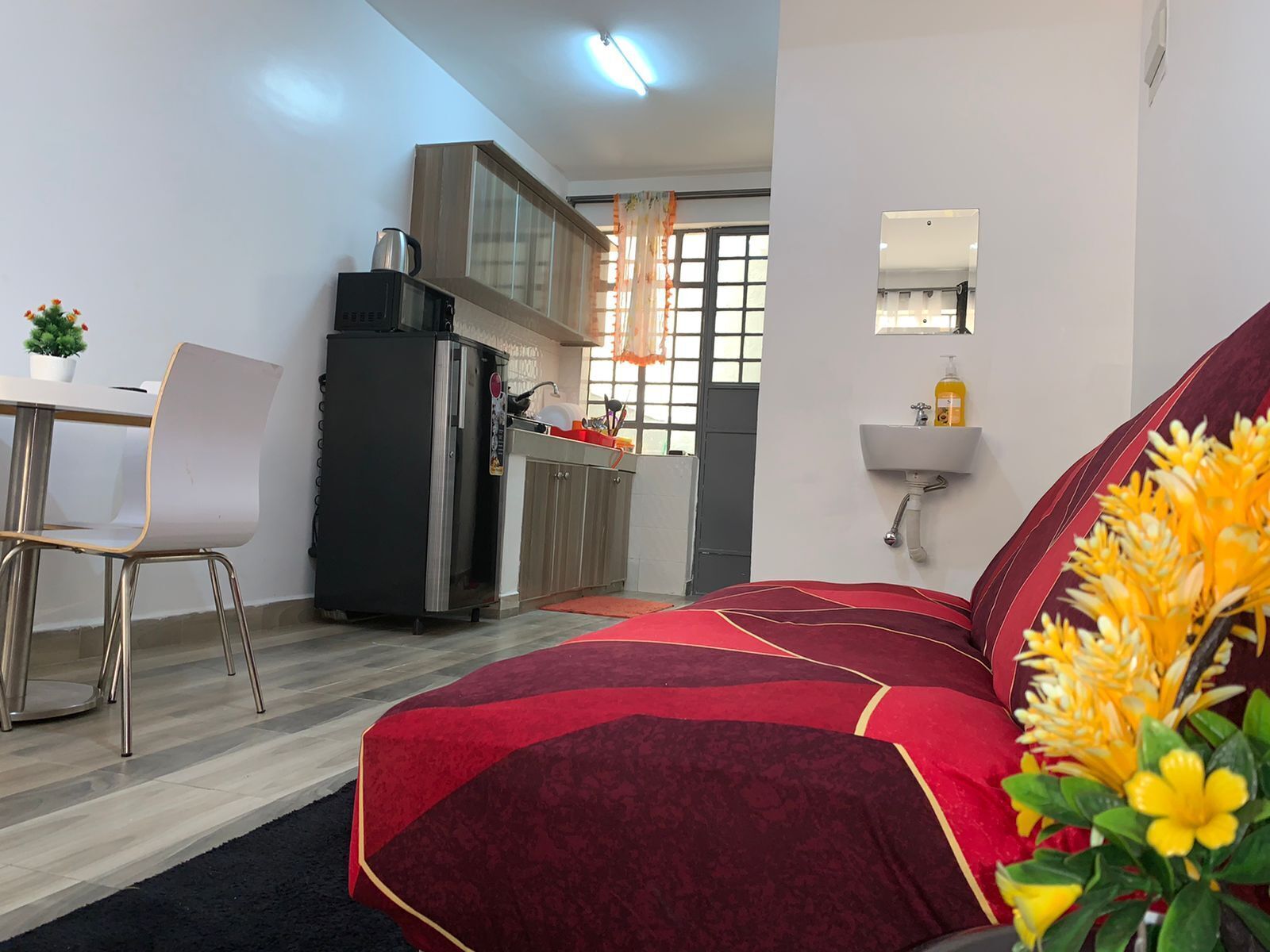 A compact bedroom with a bed, a small kitchenette, a dining area, and a bathroom.