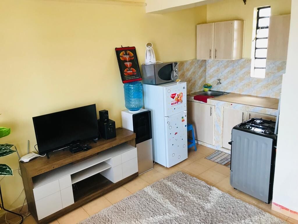 Cocina compacta con microondas, refrigerador, estufa y un lavamanos pequeño.