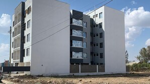 A modern multi-story building with a flat facade, large windows, and a visible staircase.