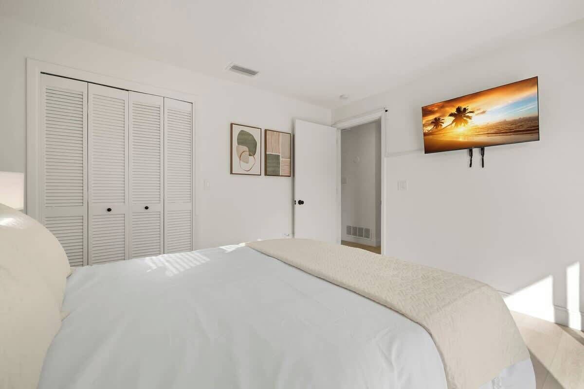Een slaapkamer met een bed, een kledingkast, een deur en een schilderij aan de muur.