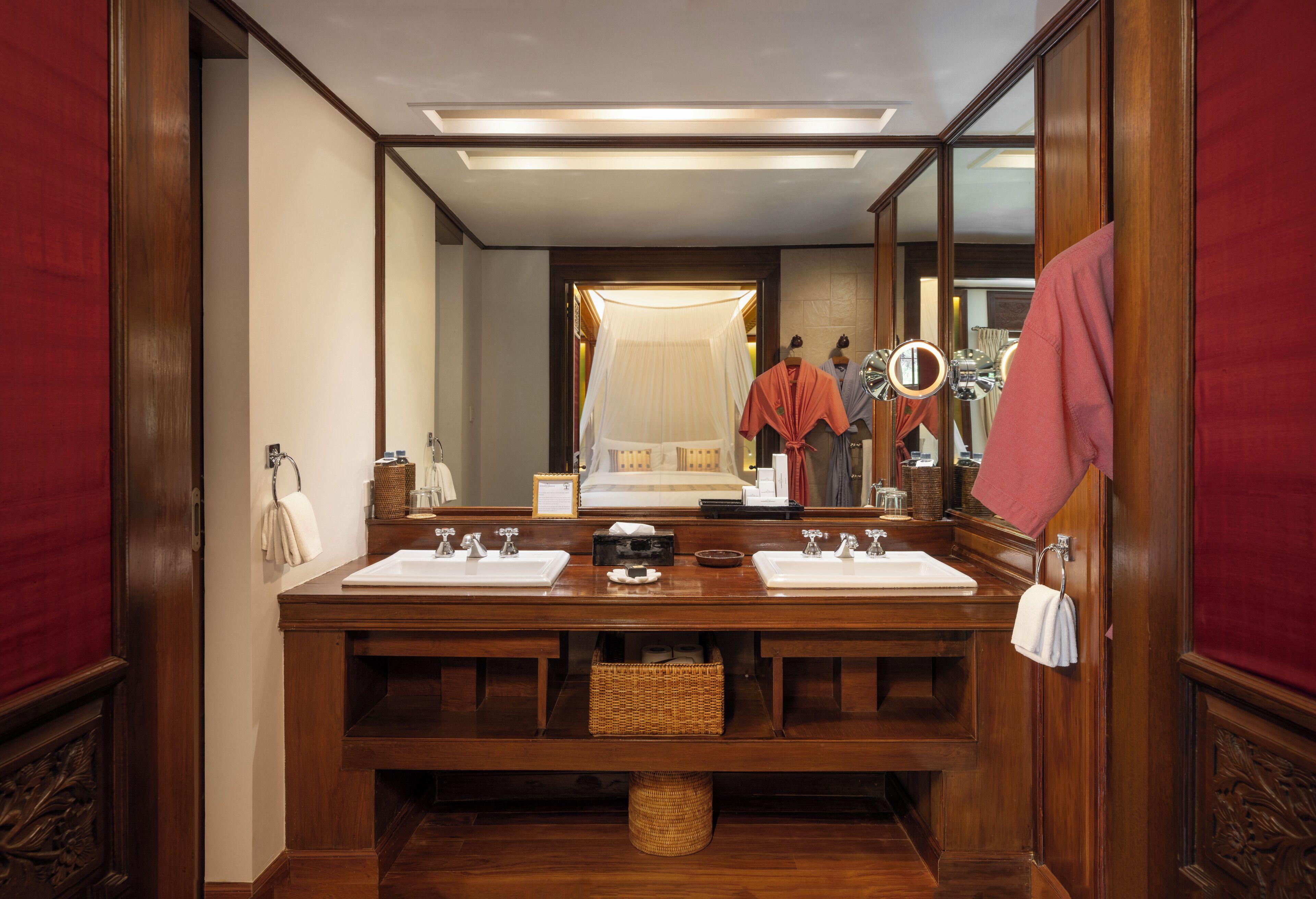 A wooden bathroom with two sinks, a large mirror, and a vanity area.