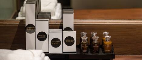 A hotel room with neatly arranged toiletries and a wooden side table.