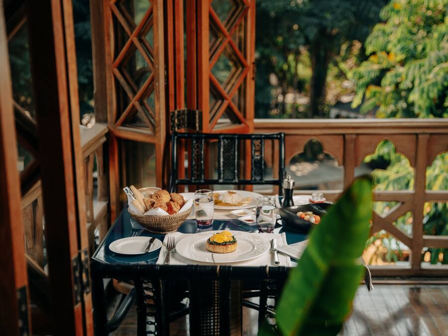A dining table set with plates, glasses, and a basket of bread.