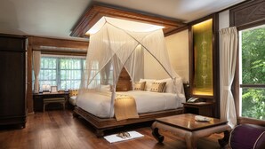 Een traditioneel ingerichte slaapkamer met hemelbed, houten meubels en uitzicht op groen.