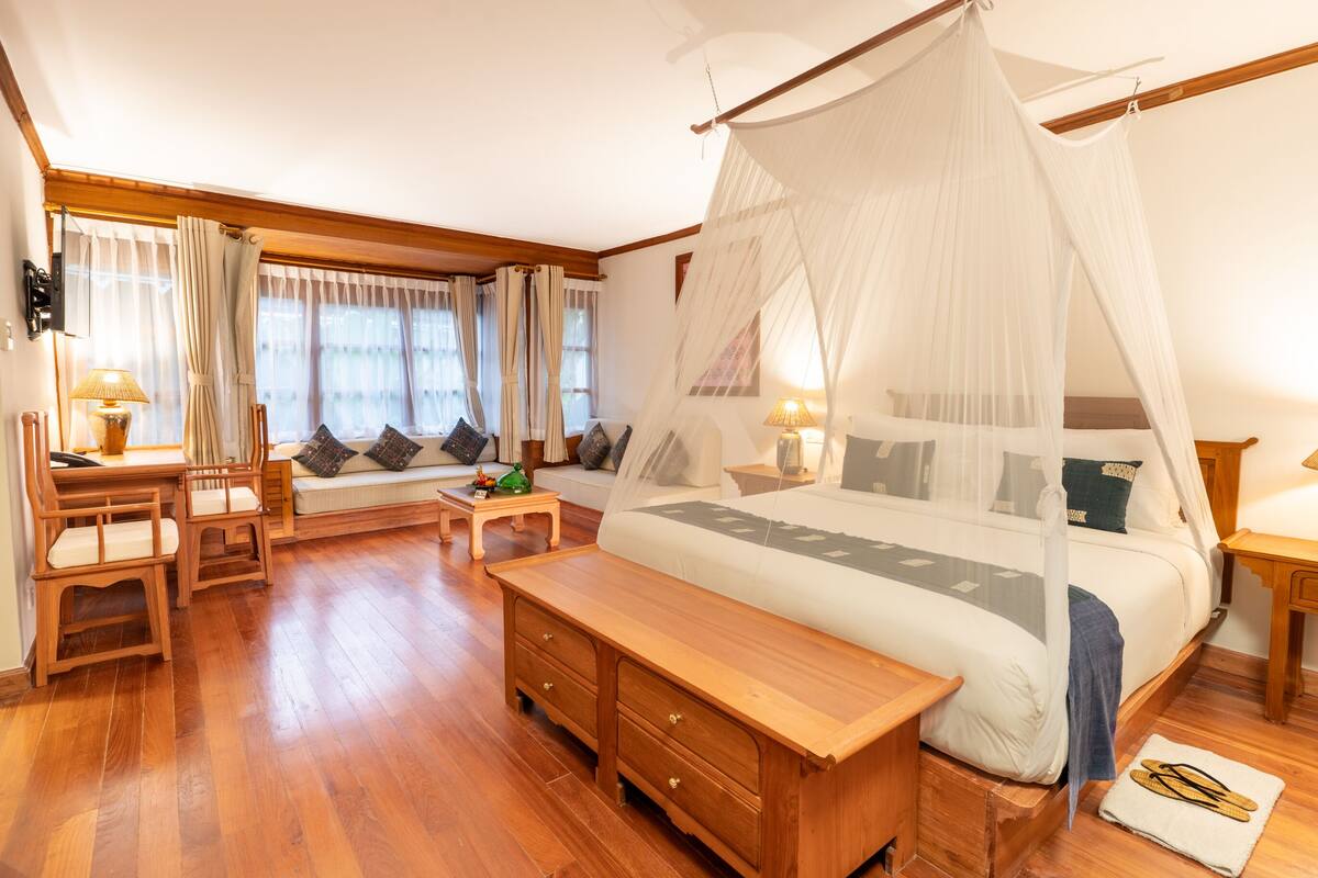 A bedroom with a large bed, wooden furniture, a bench, and a bedside table.