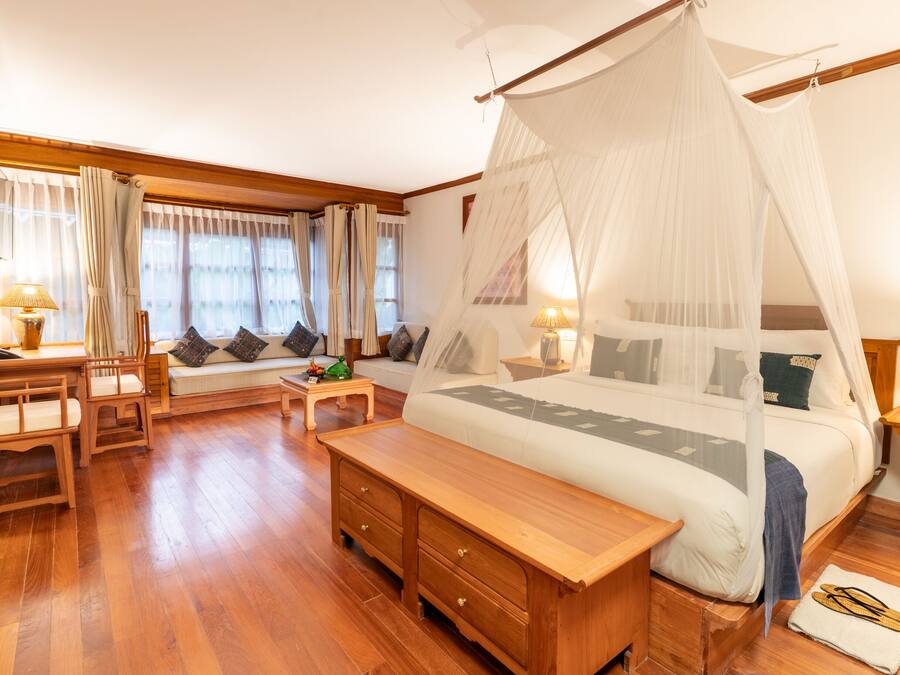Un dormitorio con una cama grande, muebles de madera, un banco y una mesita de noche.