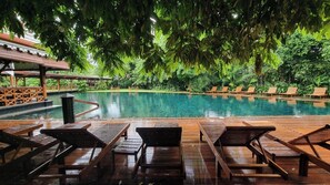 Un espace piscine doté de chaises longues en bois et d’une terrasse en bois.