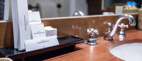 A bathroom vanity with a sink, mirror, and a tray holding toiletries.