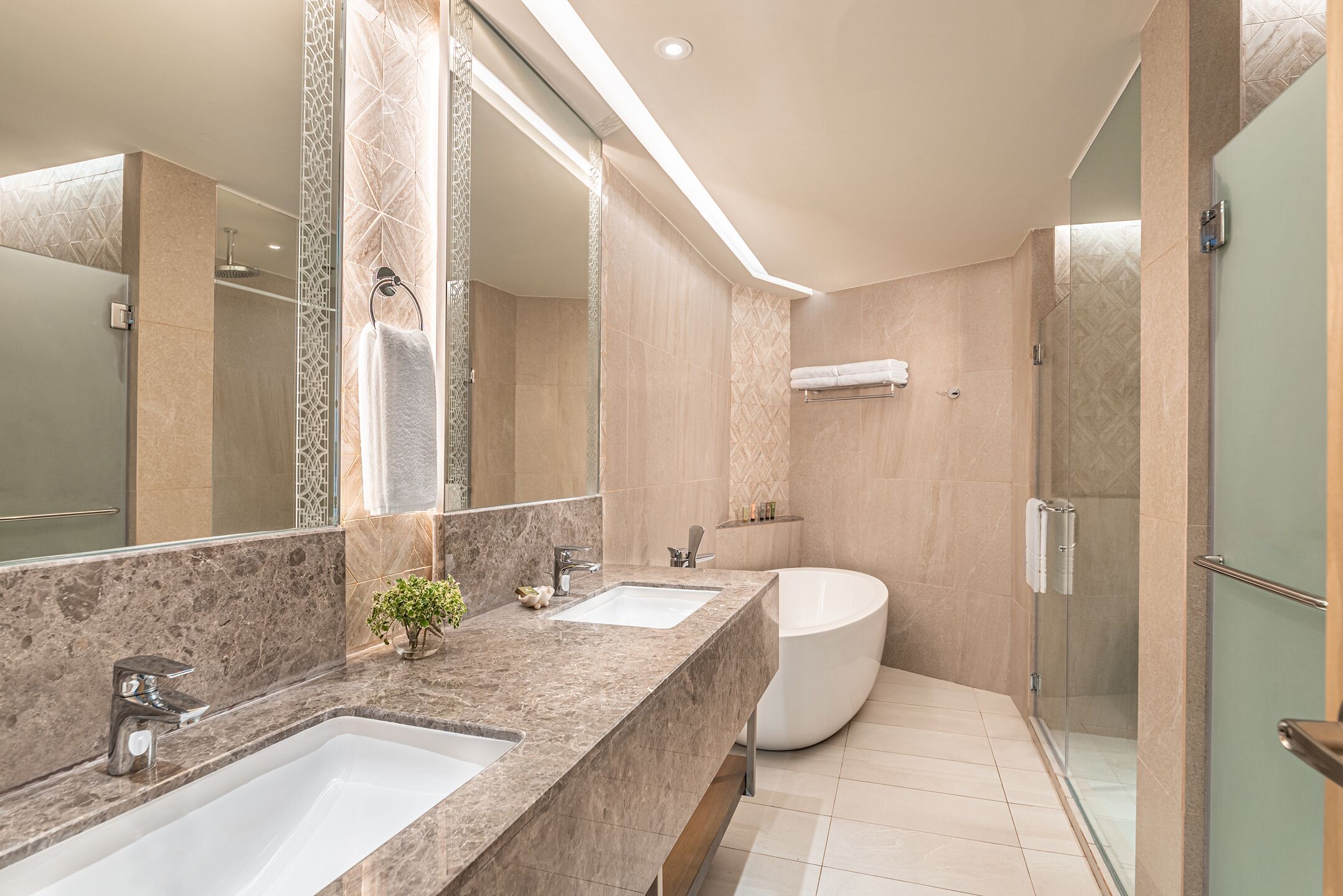 A modern bathroom with a large mirror, two sinks, a bathtub, and a glass-enclosed shower.