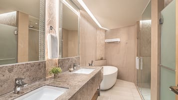 A modern bathroom with a large mirror, two sinks, a bathtub, and a glass-enclosed shower.
