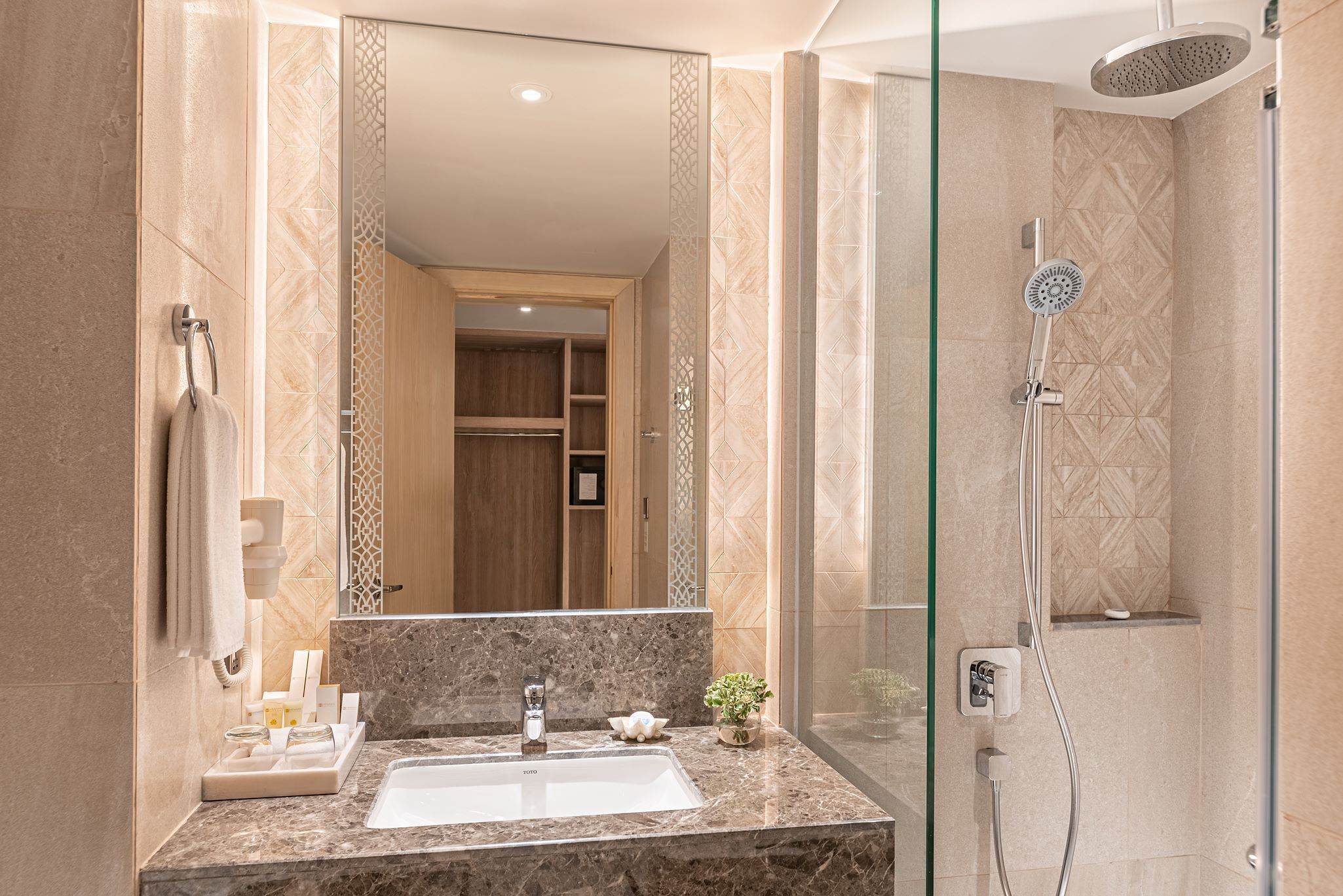 A modern bathroom with a marble sink, a glass-enclosed shower, and a wooden vanity.
