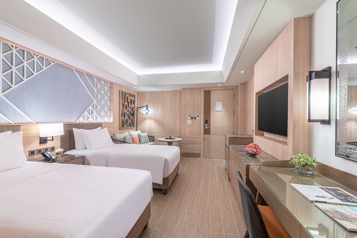 A hotel room with two beds, a desk, a television, and a decorative wall panel.