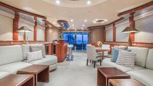 A luxurious interior with a central bar, seating area, and a view through the glass doors. - Stonehedge at Sea (Fort Lauderdale)