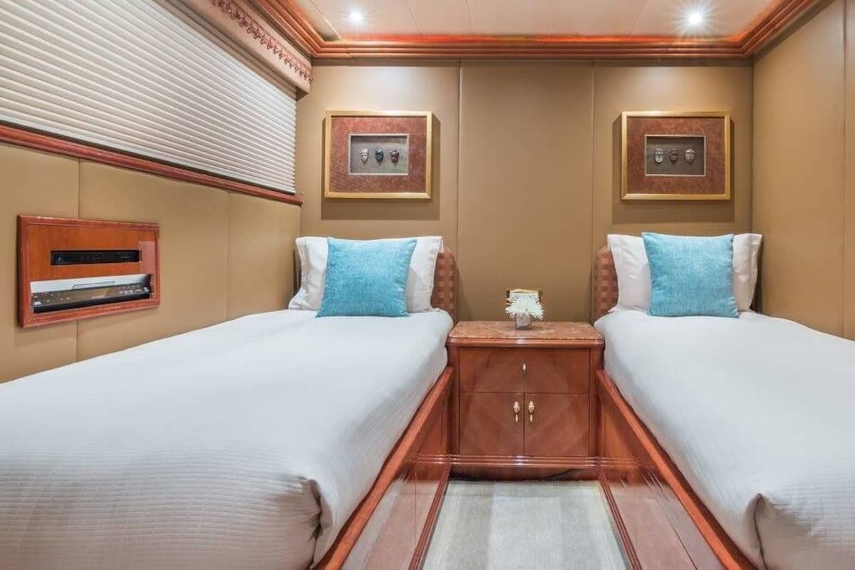 A double room with two beds, a small wooden cabinet, and a wall-mounted TV.