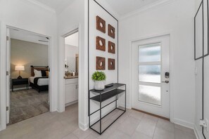 A hallway with a black metal console table, a potted plant, and a door with frosted glass panels. - Family Fun in Near Disney Star Wars, Pool, BBQ (Kissimmee)