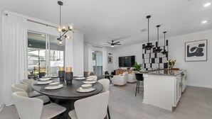 A modern kitchen with a central island, white cabinetry, and a black and white checkered backsplash. - Family Fun in Near Disney Star Wars, Pool, BBQ (Kissimmee)