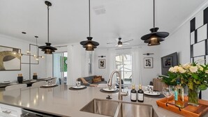 A modern kitchen with a central island, stainless steel appliances, pendant lighting, and a view to a living area. - Family Fun in Near Disney Star Wars, Pool, BBQ (Kissimmee)