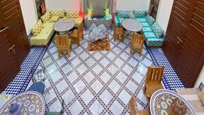 A room with a patterned floor, a central seating area with cushions, a chandelier, and decorative wall panels. - Riad Fes Colors & Spa (Fes)