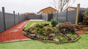 A landscaped garden with a paved path, a small water feature, and various plants.
