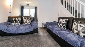 A modern bedroom with a bed, a sofa, and a staircase.