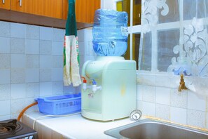 A kitchen with a water dispenser, a blue basket, and a stainless steel sink.