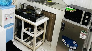 A compact kitchen with a gas stove, a microwave, and a water dispenser.