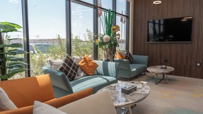 A modern living room with a sofa, coffee table, and a flat-screen TV mounted on the wall.