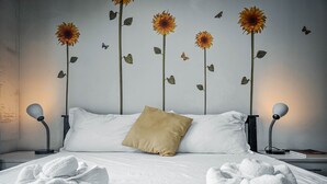 Un lit bien fait, avec des draps blancs, un oreiller beige et deux serviettes.