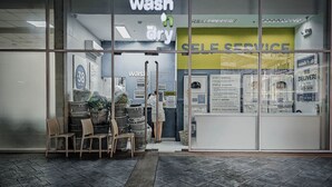 Une laverie professionnelle offrant un service de lavage et de séchage, avec une signalétique bien visible et des paniers empilés à l’extérieur.
