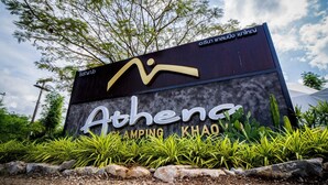 Een bord met de tekst 'Athena Camping Khao', met een modern ontwerp en een logo boven de naam.