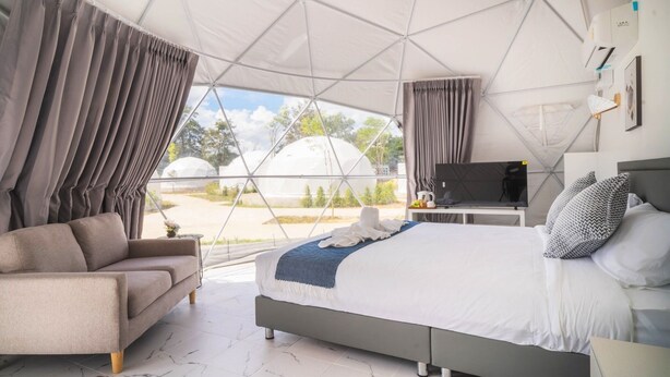 Een moderne slaapkamer met een bed, een bank en een televisie. De kamer heeft een groot raam en gordijnen.