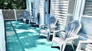 A porch with white Adirondack chairs and a white picket fence.