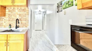 A kitchen with yellow cabinets, a black faucet, and a tiled backsplash.