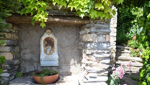 A stone wall with a small shrine and a potted plant.