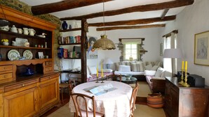 A rustic dining area with wooden furniture, a table with a lace tablecloth, and a hanging light fixture.