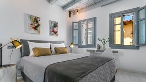 A modern bedroom with a large bed, two bedside lamps, and artwork on the walls.